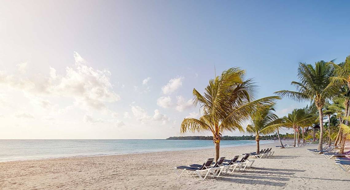 Strand mit Sonnenliegen und Palmen am Barcelo Maya Palace Hotel