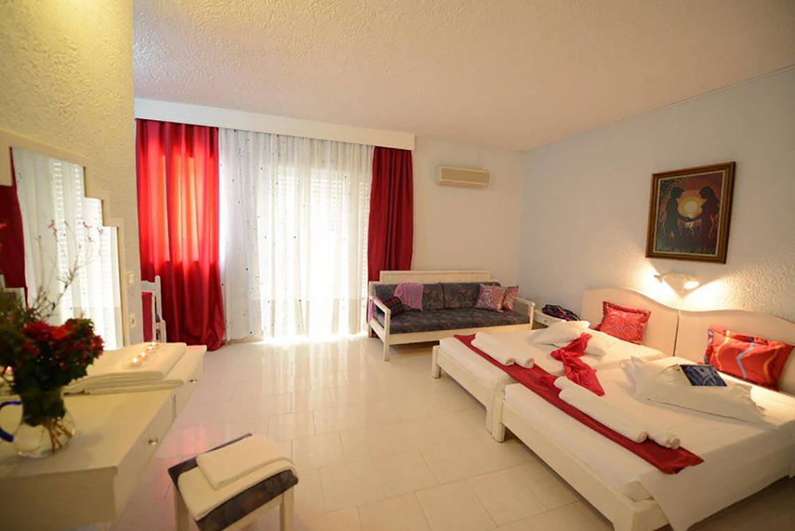 Schlafzimmer im Golden Star Hotel in Kos mit zwei Betten, rotem Dekor und einem Sofa.