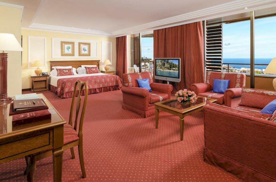 Innenansicht der Botanico & The Oriental Spa Garden Suite mit Meerblick, roten Möbeln und Fernseher.