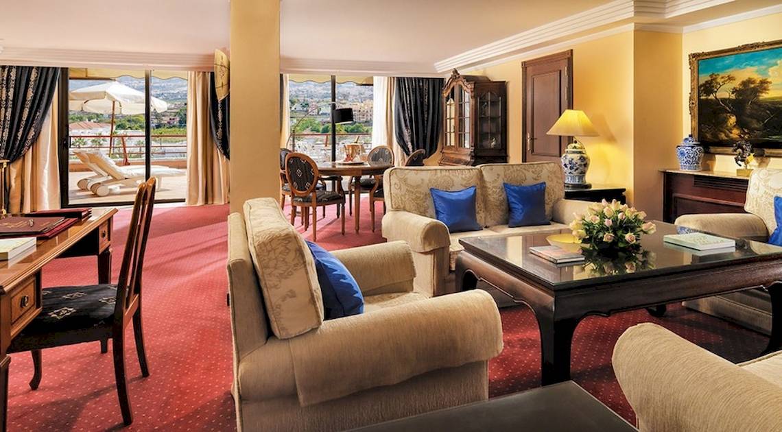 Wohnzimmer im Botanico & The Oriental Spa Garden Hotel mit gelben Wänden, rotem Teppich und blauen Kissen.