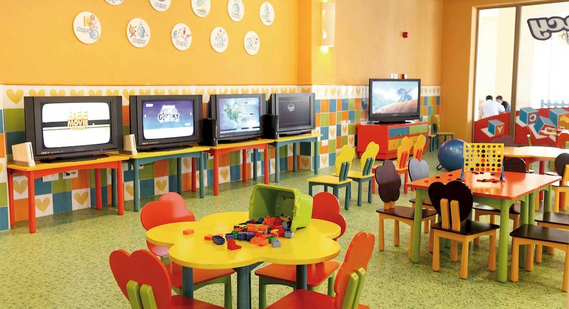 Kinderspielzimmer im Barcelo Maya Palace mit bunten Möbeln, Fernsehgeräten und Spielzeug.