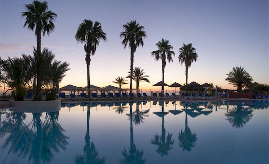 Sonnenuntergang am Pool des Belambra Clubs Pineto mit Palmen und Sonnenliegen.