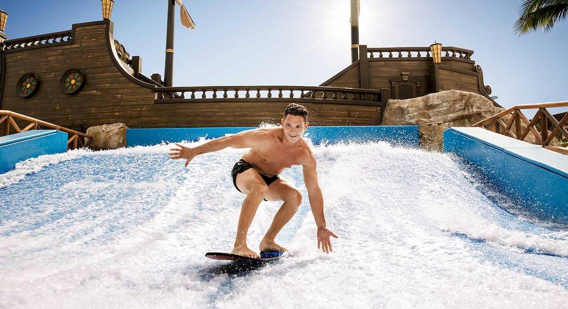 Ein Mann surft auf einer künstlichen Welle im Wasserpark des Barcelo Maya Palace.