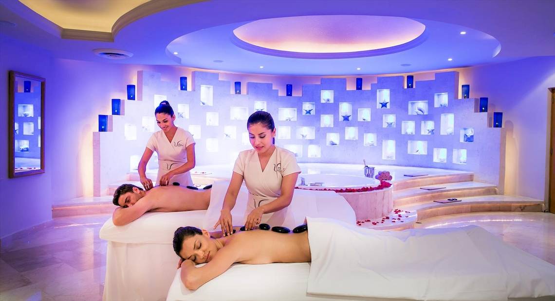 Im Spa des Barcelo Maya Palace werden Gäste bei einer Massagebehandlung verwöhnt, mit blauen Lichtern und Sternen an der Wand.