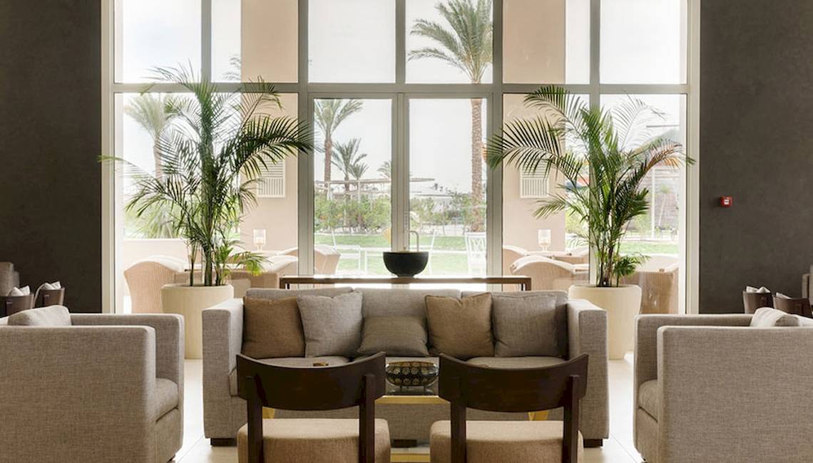 Lobby-Loungebereich des Jaz Aquaviva Hotels mit großen Fenstern, Pflanzen und Möbeln.