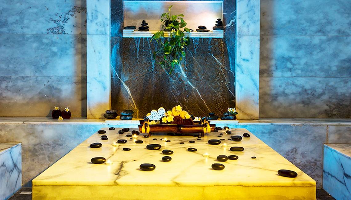 Behandlungsbereich im Jaz Aquaviva Spa mit Marmortisch, schwarzen Steinen und Kerzen.