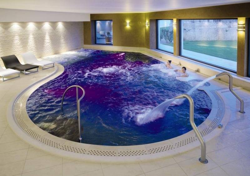 Schwimmbad im MIRA Acaya Golf Resort & SPA mit zwei Personen und Lounge-Sesseln