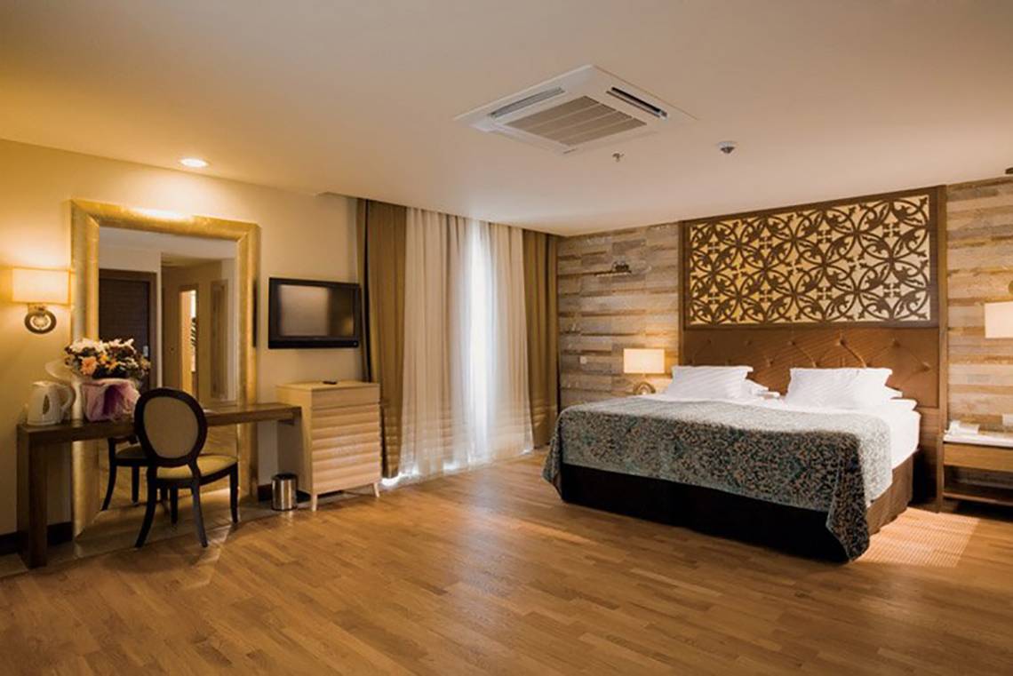 Ein Schlafzimmer im Melas Lara Hotel mit einem großen Bett, Dekor und Möbeln.