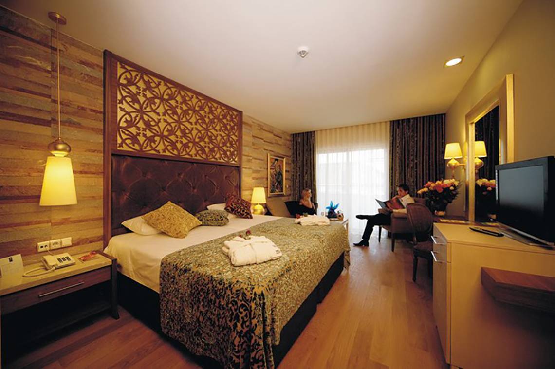 Ein Hotelzimmer im Melas Lara Hotel mit einem großen Bett und modernen Möbeln.