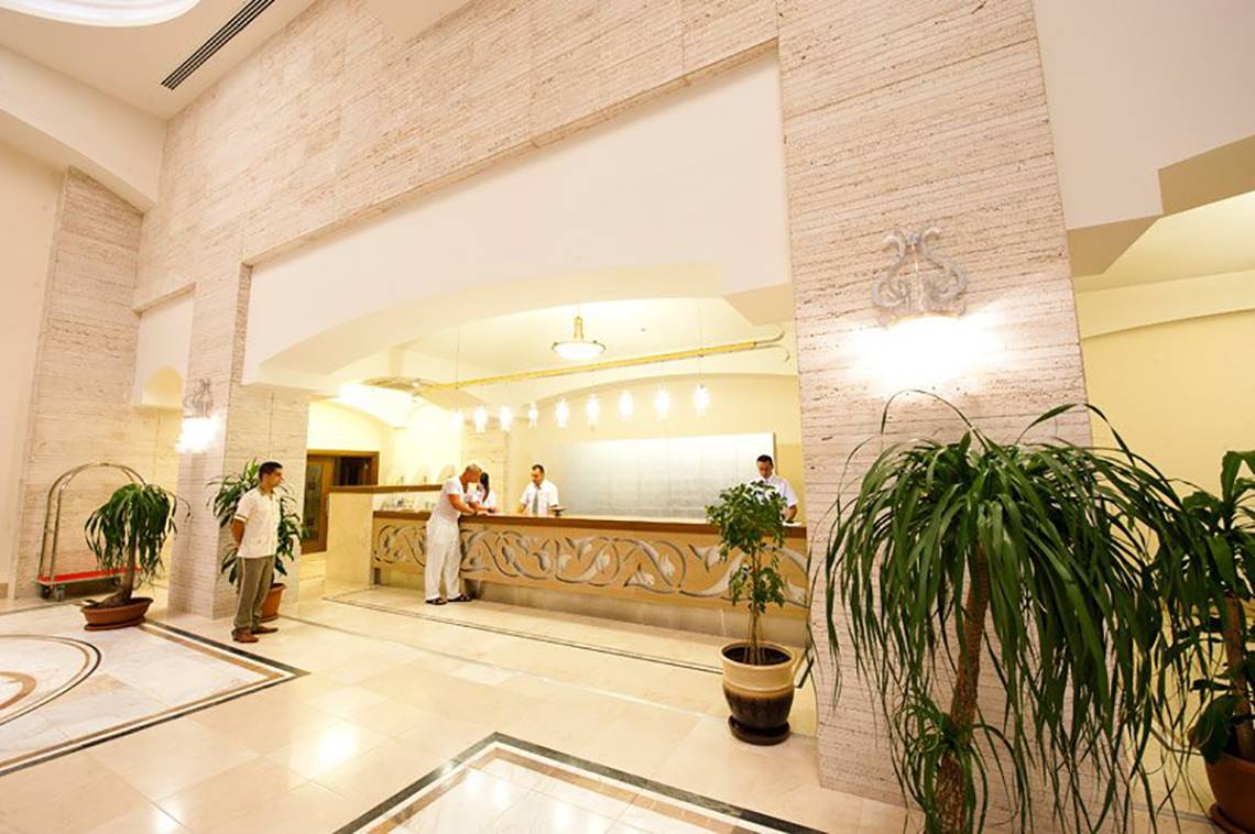 Empfangsbereich des Melas Lara Hotels mit Rezeption und Gästen.