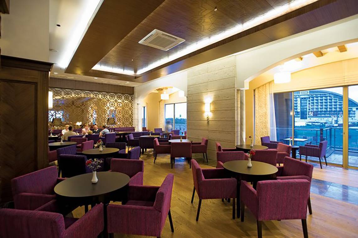 Innenbereich des Melas Lara Hotels mit gepolsterten Stühlen und Tischen in einem Restaurant.