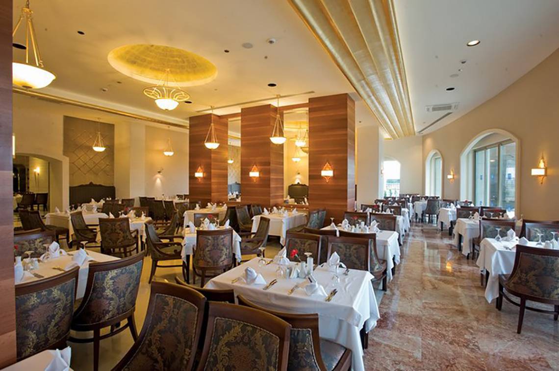 Innenansicht des Restaurants im Melas Lara Hotel mit gedeckten Tischen und Holzsäulen.