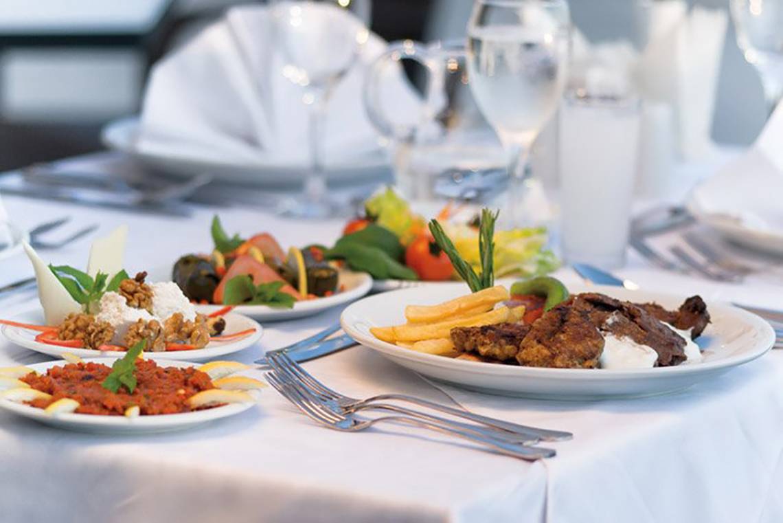 Gedeckter Tisch im Melas Lara Hotel mit verschiedenen Gerichten und Getränken.