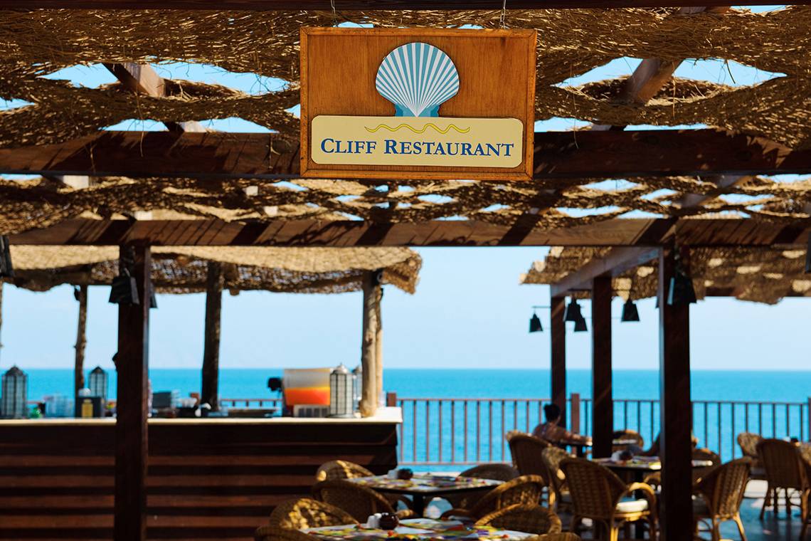 Terrasse des Cliff Restaurants mit Blick auf das Meer und einigen Gästen.