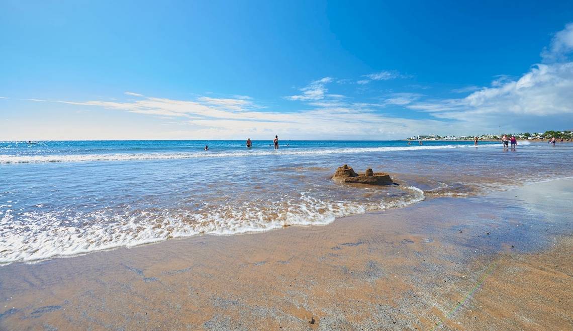 Strandszene mit Hipotels La Geria Hotel, Sandburg und Schwimmern