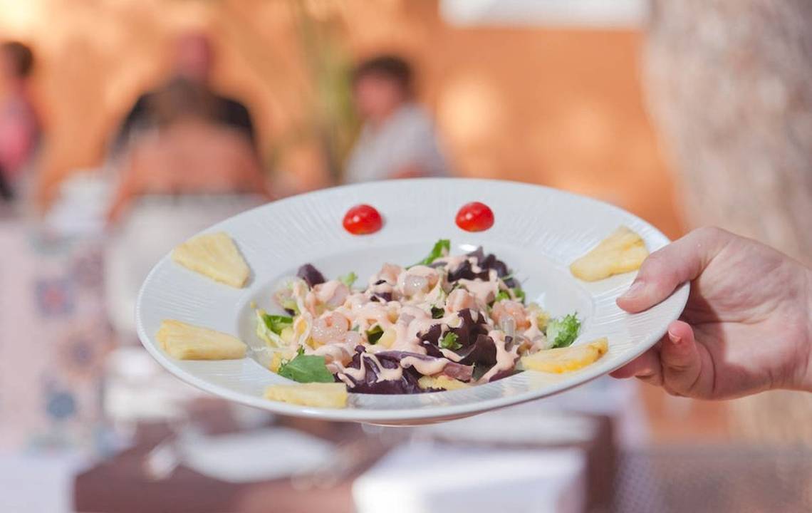 Ein Salat auf einem weißen Teller mit Tomaten und Ananas im Restaurant.