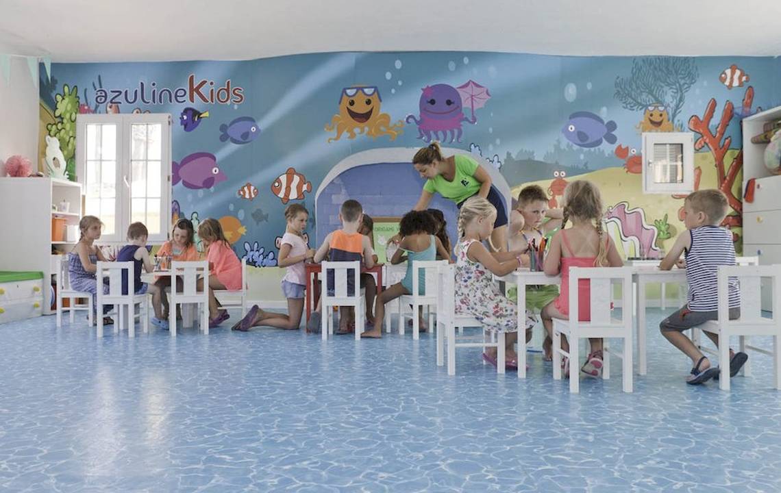 Kinder sitzen in einem blauen Raum mit Meereslebewesen an der Wand.