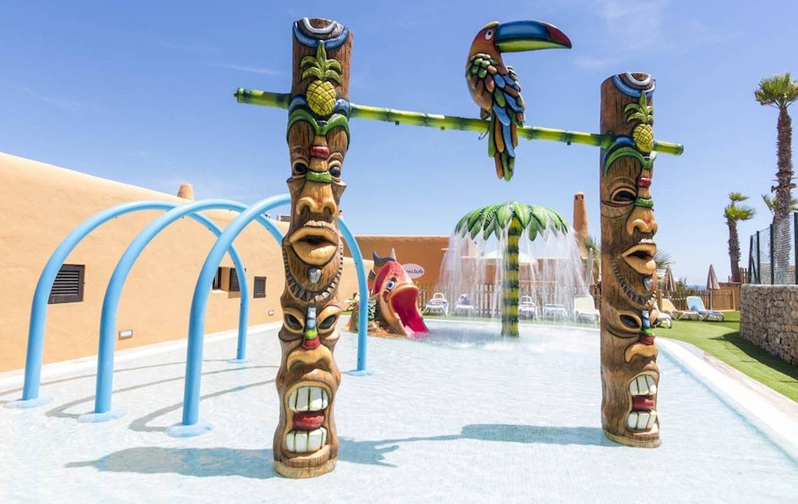 Tropische Wasserlandschaft im Cala Martina by Llum Hotel mit bunten Tiki-Figuren und Wasserrutsche.