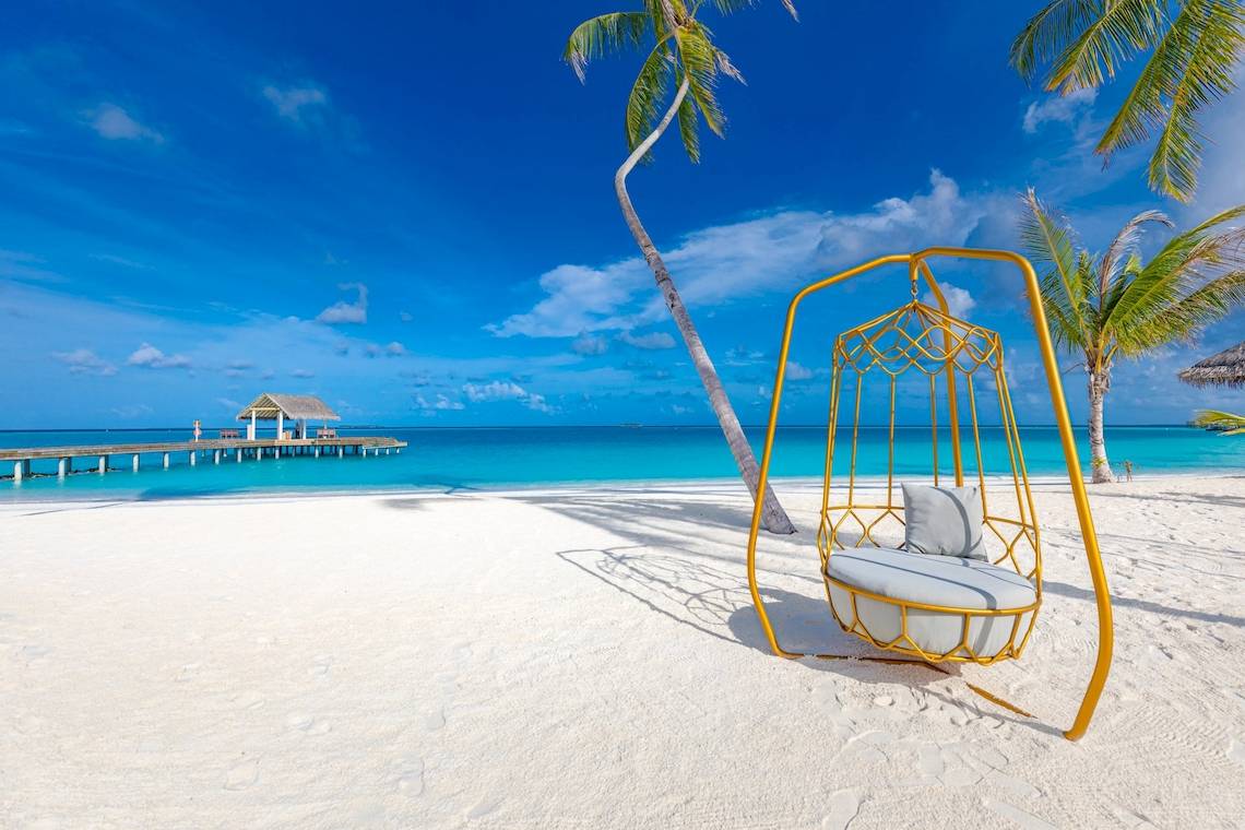 Strand mit Hängematte und Hotel Sun Siyam Iru Veli im Hintergrund