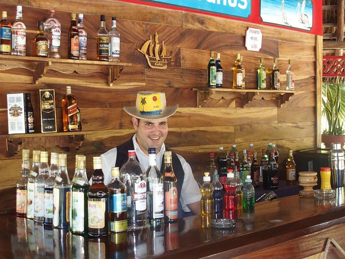 Ein Barkeeper im ROC Arenas Doradas Hotel steht hinter einer Bar mit vielen Alkoholflaschen.
