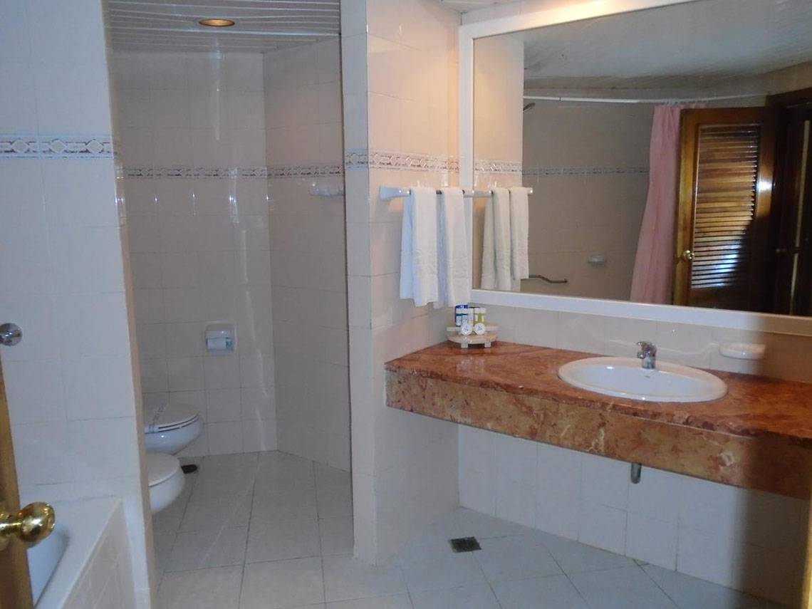 Ein Badezimmer des ROC Arenas Doradas Hotels mit einer Dusche, Toilette, Waschbecken und Spiegel.