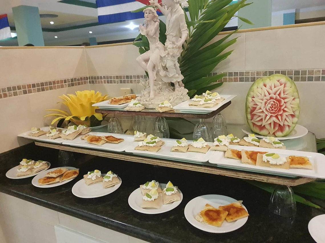 Foto des Speisenbuffets im ROC Arenas Doradas Hotel, mit verschiedenen Gerichten und einer Wassermelonenskulptur.