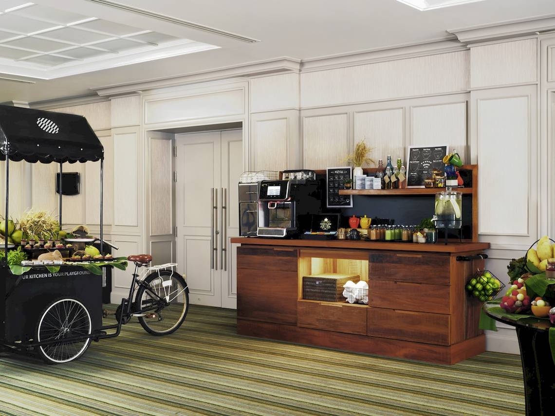 Innenbereich des Pullman Phuket Panwa Beach Resort mit Früchtewagen, Fahrrad und Bar.