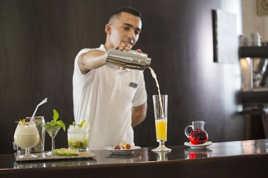 Ein Barkeeper im Hipotels La Geria Hotel schenkt Cocktails in Gläser ein.