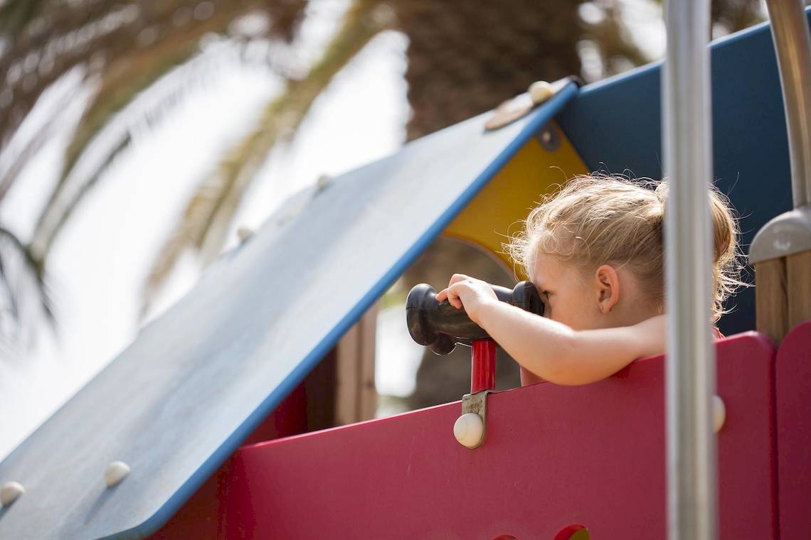 Kleines Kind am Spielplatz mit einem Fernrohr