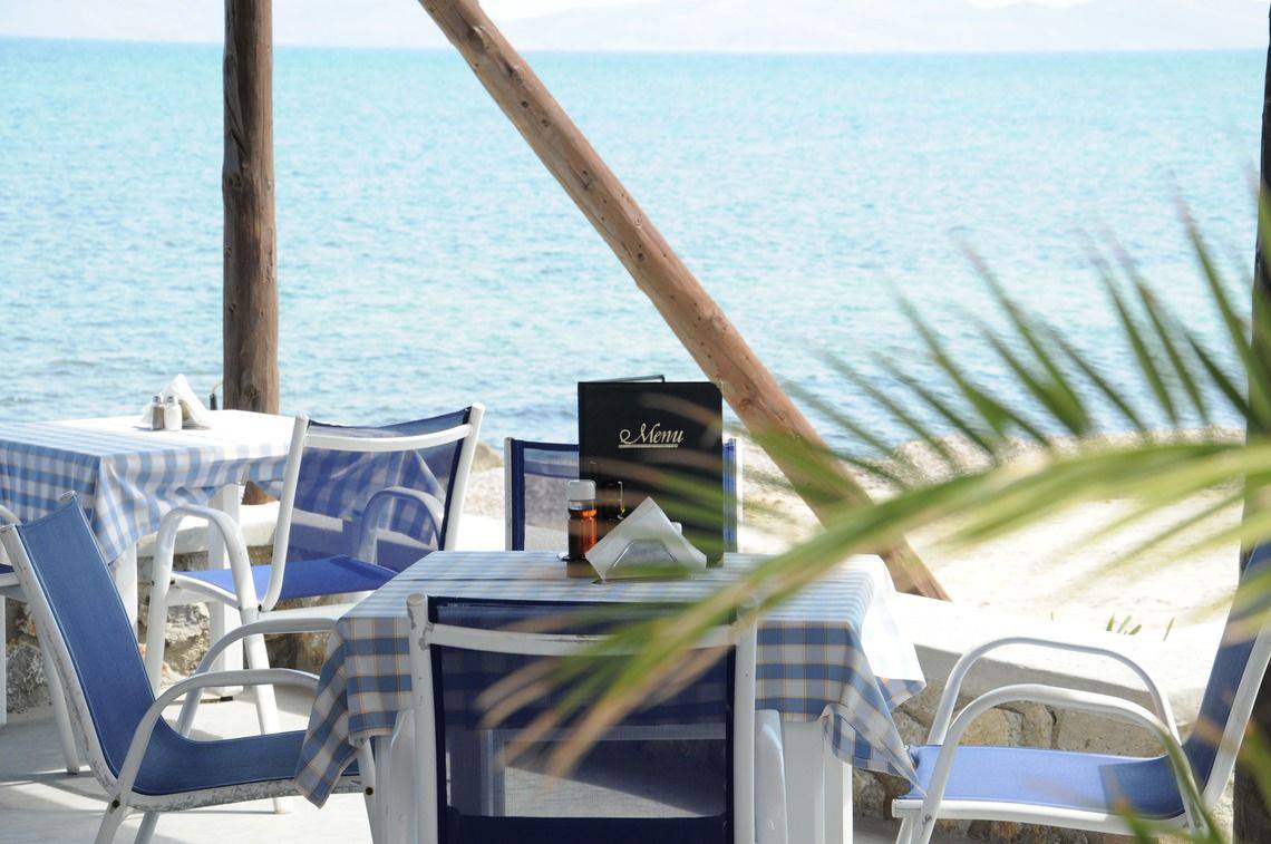 Strandrestauranttisch mit Menü und Blick auf das Meer, Mastichari Bay