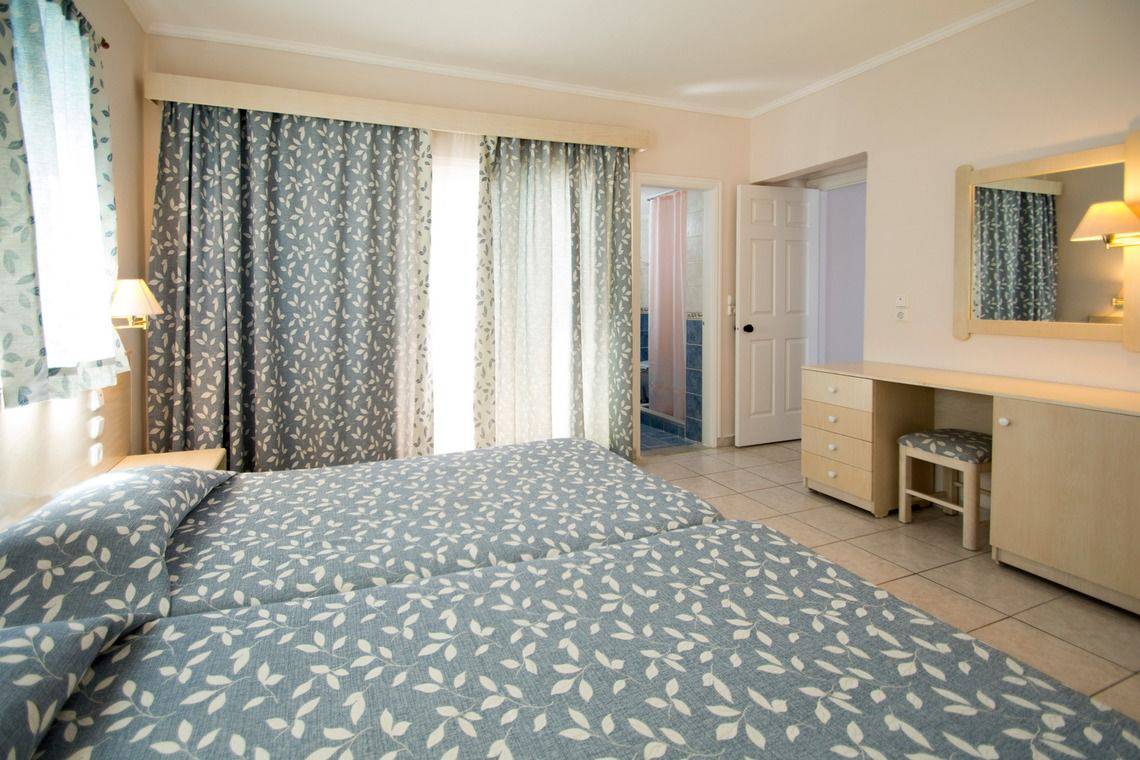 Doppelzimmer im Mastichari Bay Hotel mit zwei Betten, Schreibtisch und Spiegel.