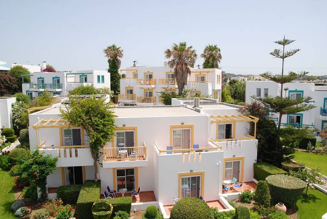 Luftaufnahme des Mastichari Bay Hotels mit mehreren weißen Gebäuden und gelben Akzenten.