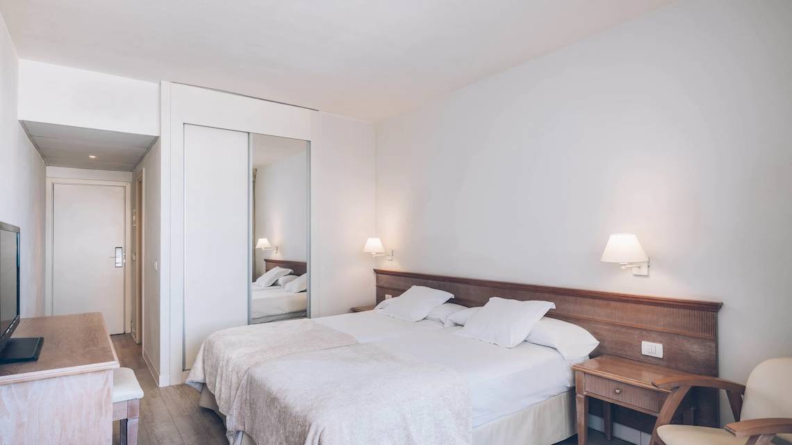 Hotelzimmer im Iberostar Las Dalias mit zwei Betten, Fernseher, Nachttisch und Spiegel.