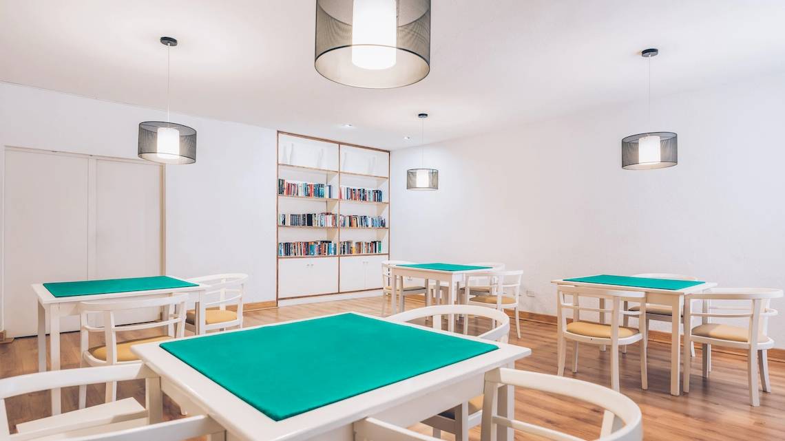 Speisesaal im Iberostar Las Dalias Hotel mit weißen Tischen und Stühlen, Bücherregal und Deckenlampen.