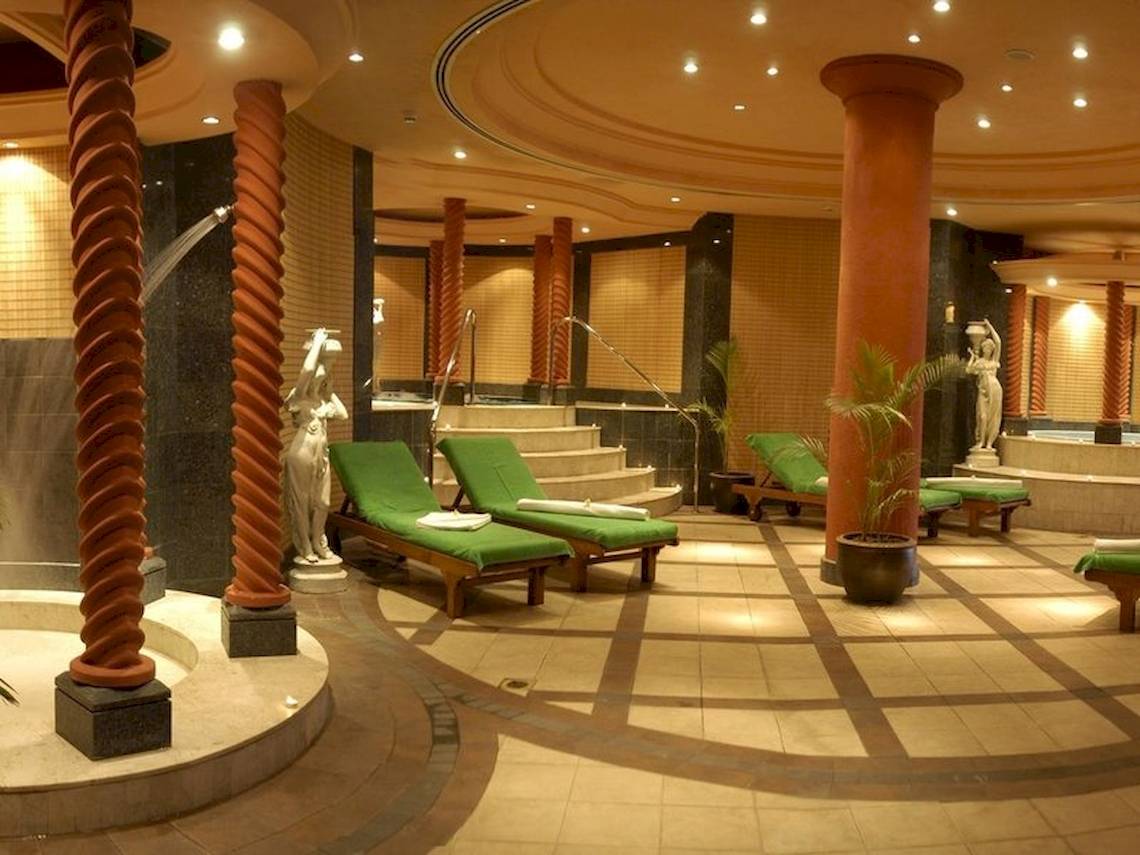 Wellnessbereich im Le Meridien Ile Maurice Hotel mit grünen Liegen, Statuen und Pflanzen.