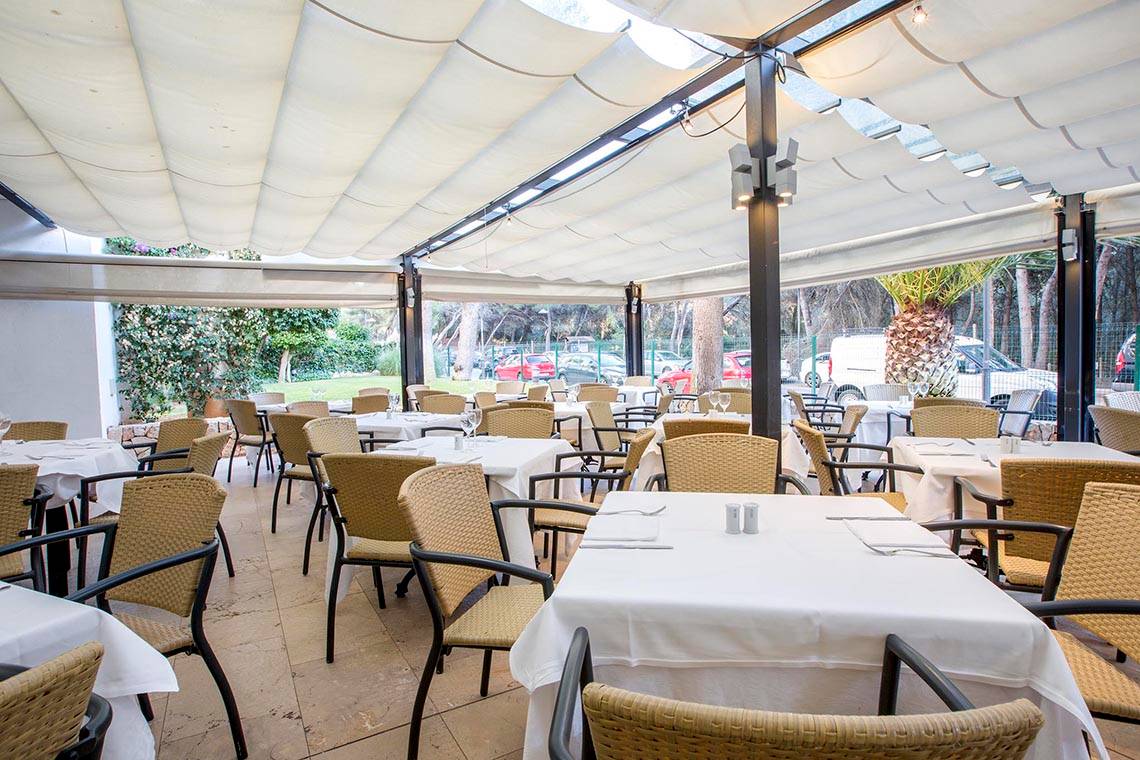 Restaurantterrasse des Hipotels Bahia Grande mit Tischen und Stühlen unter einem Dach.