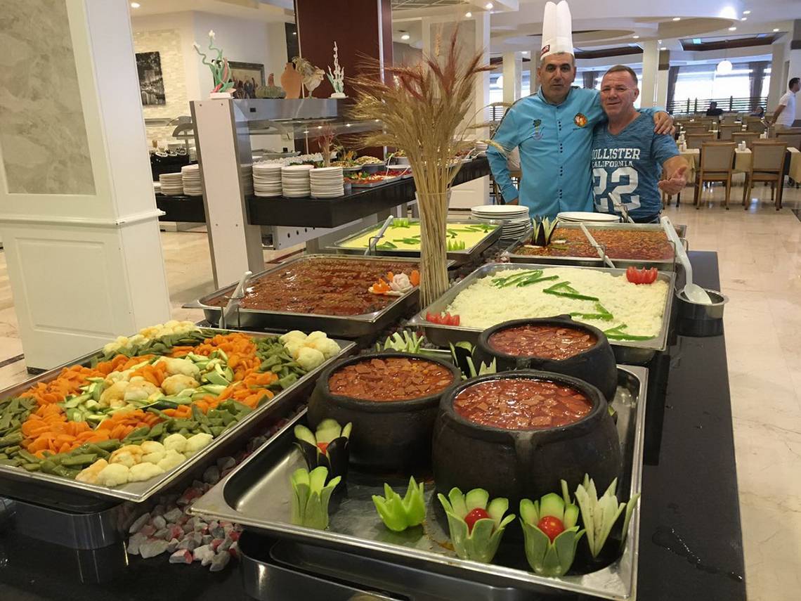 Buffet im Riviera Hotel & Spa mit verschiedenen Gerichten und zwei Männern im Hintergrund.