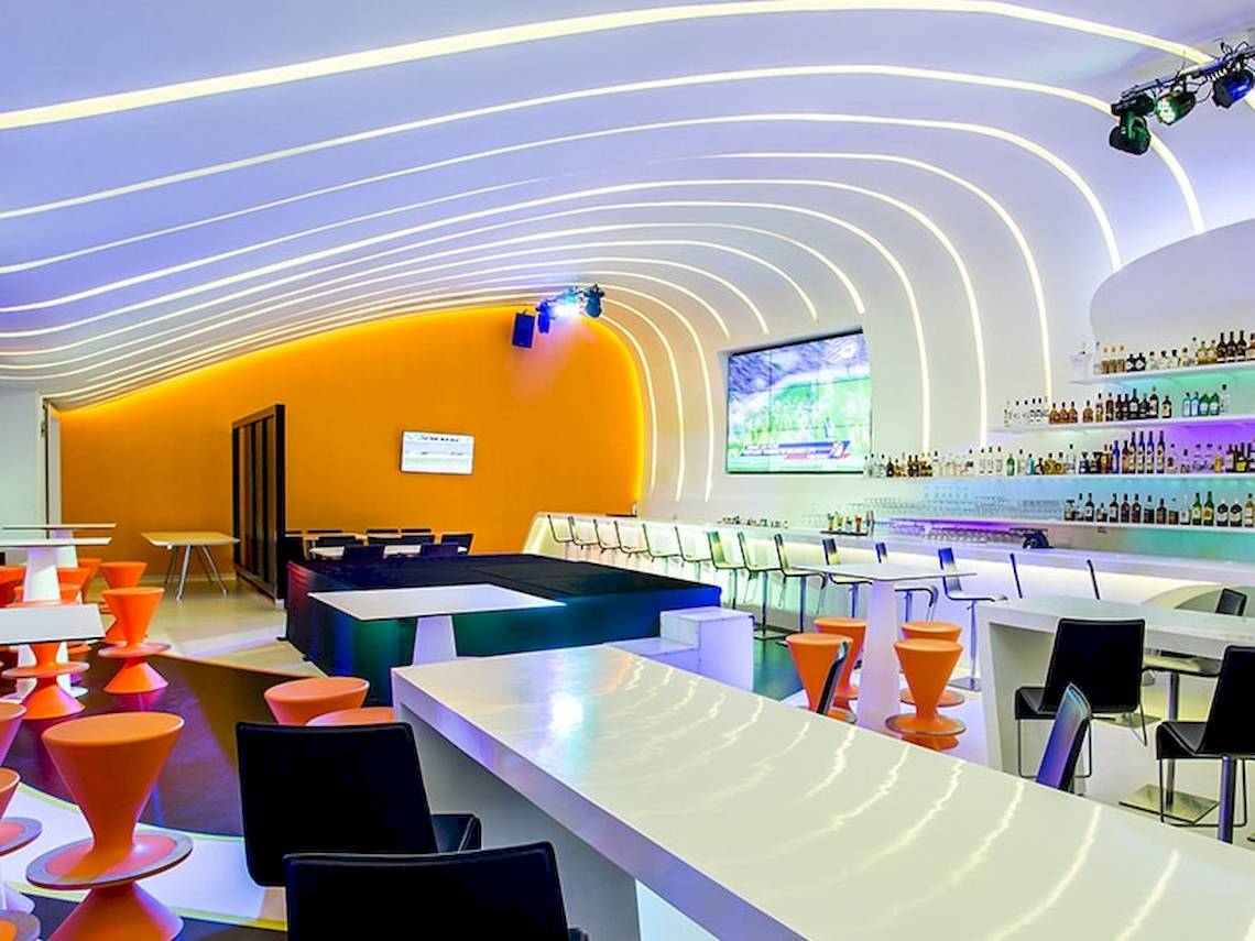 Innenansicht der Lounge im Temptation Cancun Resort mit geschwungener Decke, orangefarbenen Wänden und moderner Einrichtung.