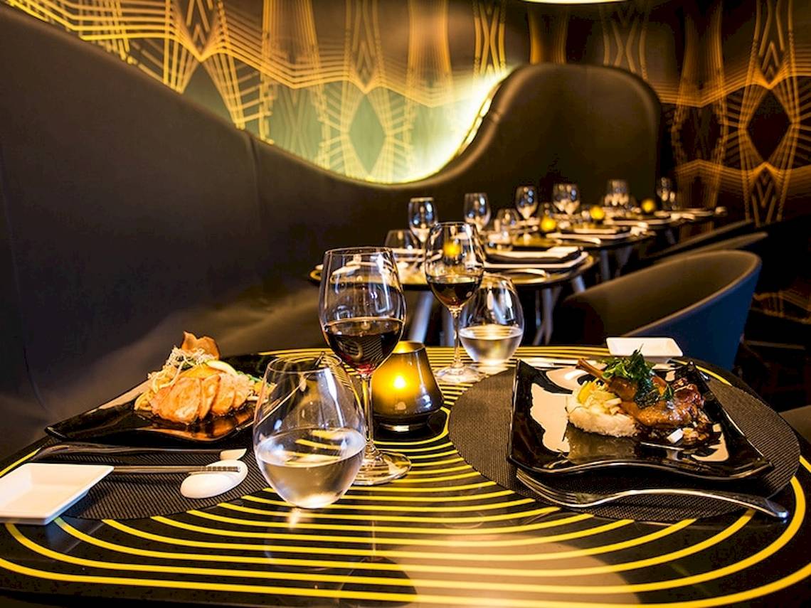 Ein Tisch im Temptation Cancun Resort Hotel mit Gerichten und Getränken, gerahmt von goldenen Linien.