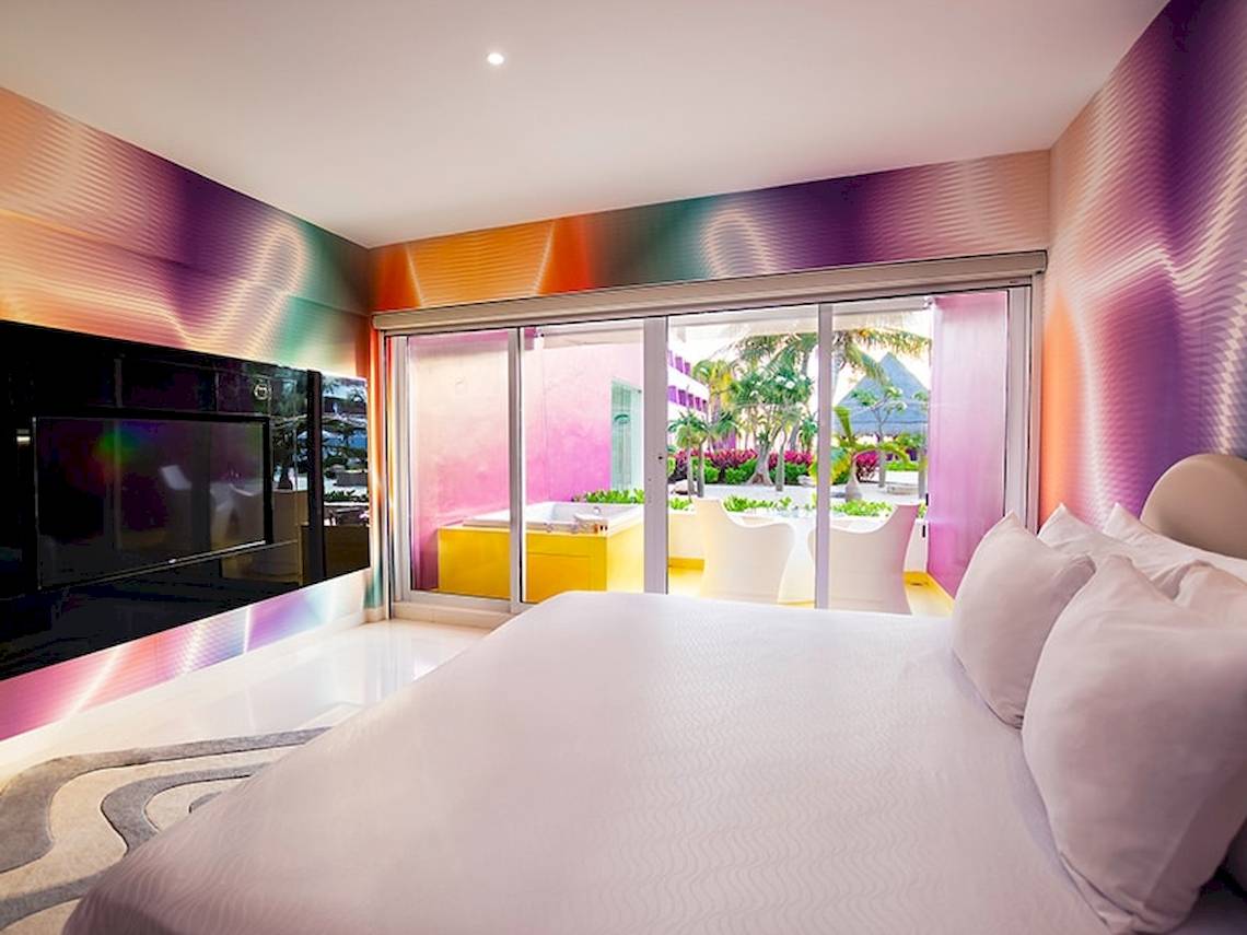 Schlafzimmer im Temptation Cancun Resort mit bunten Wänden, einem großen Bett und einer Terrasse