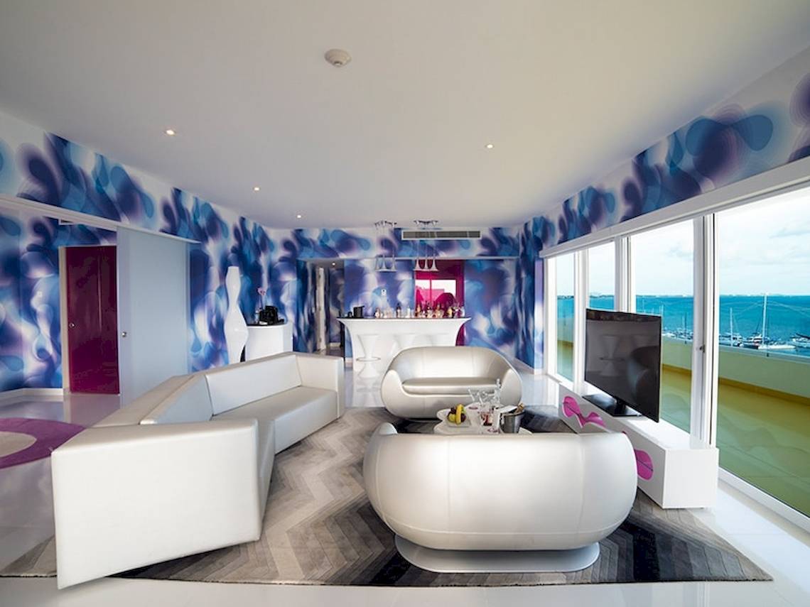 Wohnzimmer im Temptation Cancun Resort mit blauen und weißen Wänden, weißen Möbeln und Blick auf das Meer.