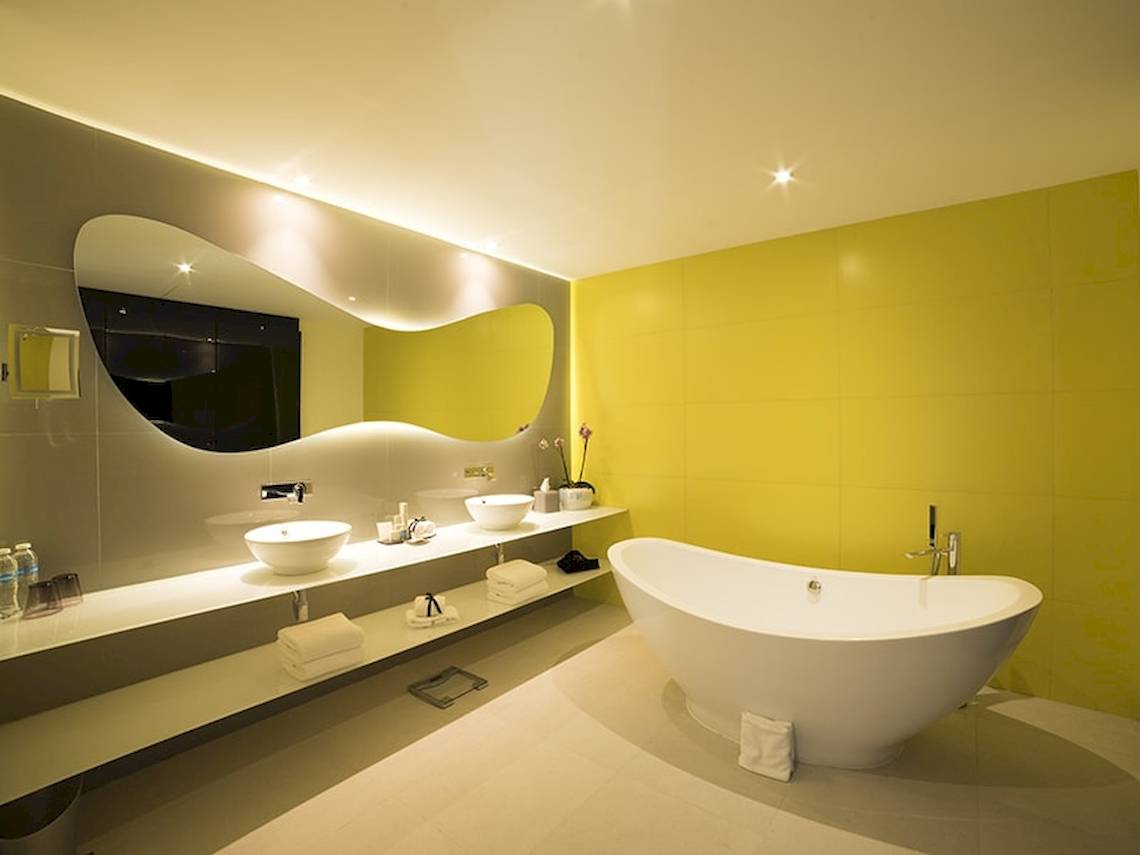 Ein modernes Badezimmer mit zwei Waschbecken, einer Badewanne und gelben Wänden.