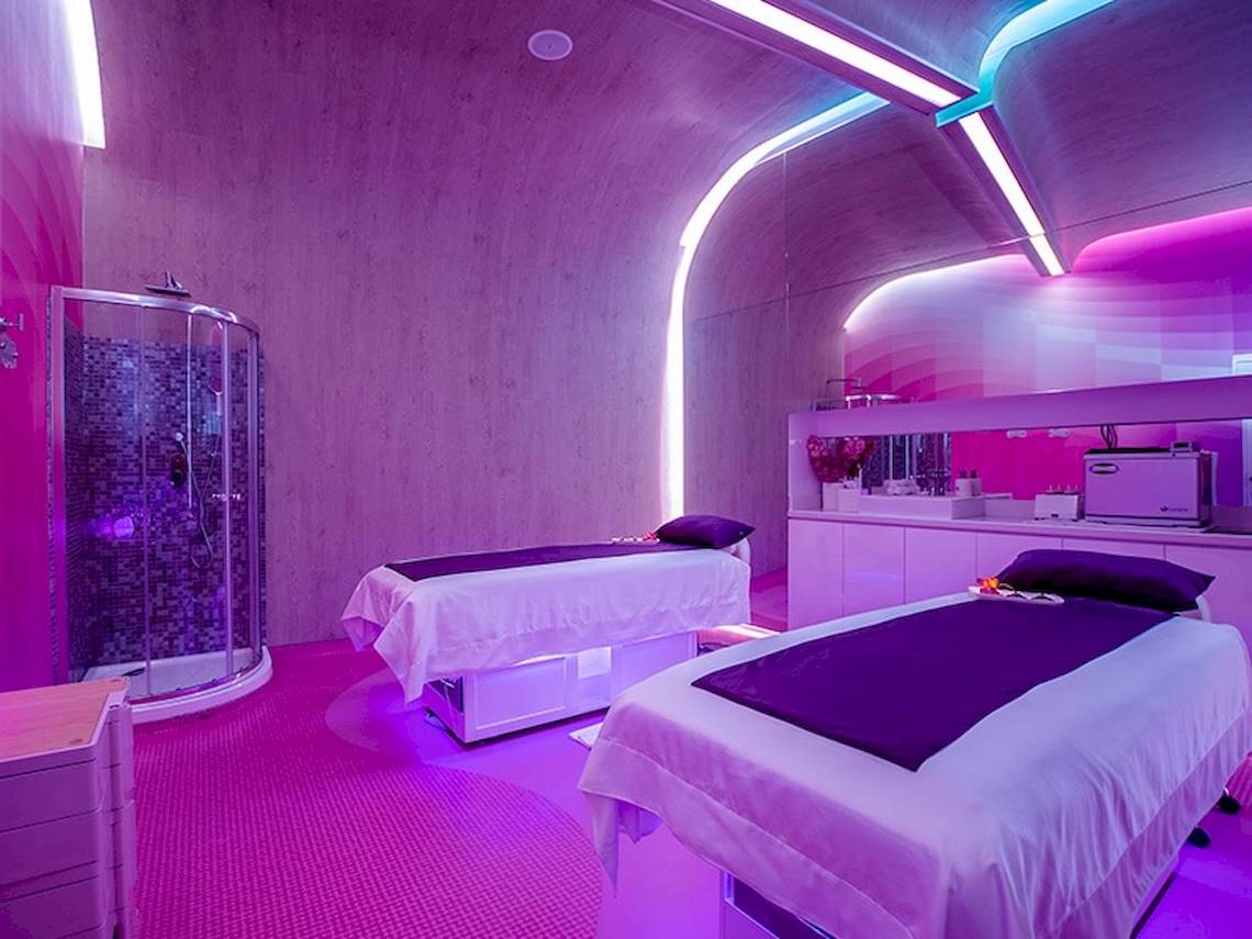 Zwei Betten im Temptation Cancun Resort Behandlungsraum mit lila Beleuchtung und modernem Design.
