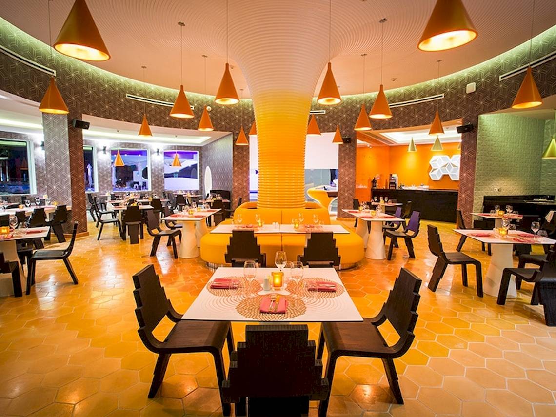Innenansicht des Restaurants im Temptation Cancun Resort mit runden Tischen und Stühlen.