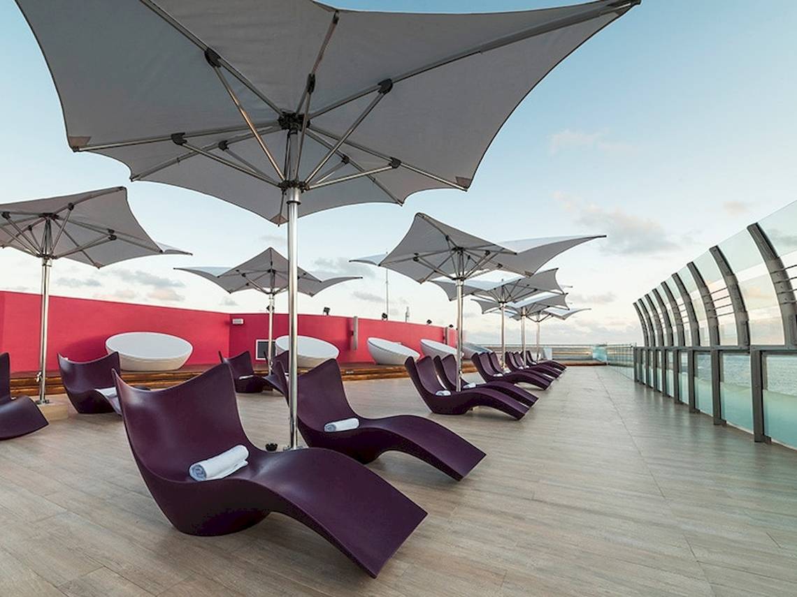Loungebereich im Temptation Cancun Resort mit roten Liegen und weißen Sonnenschirmen.