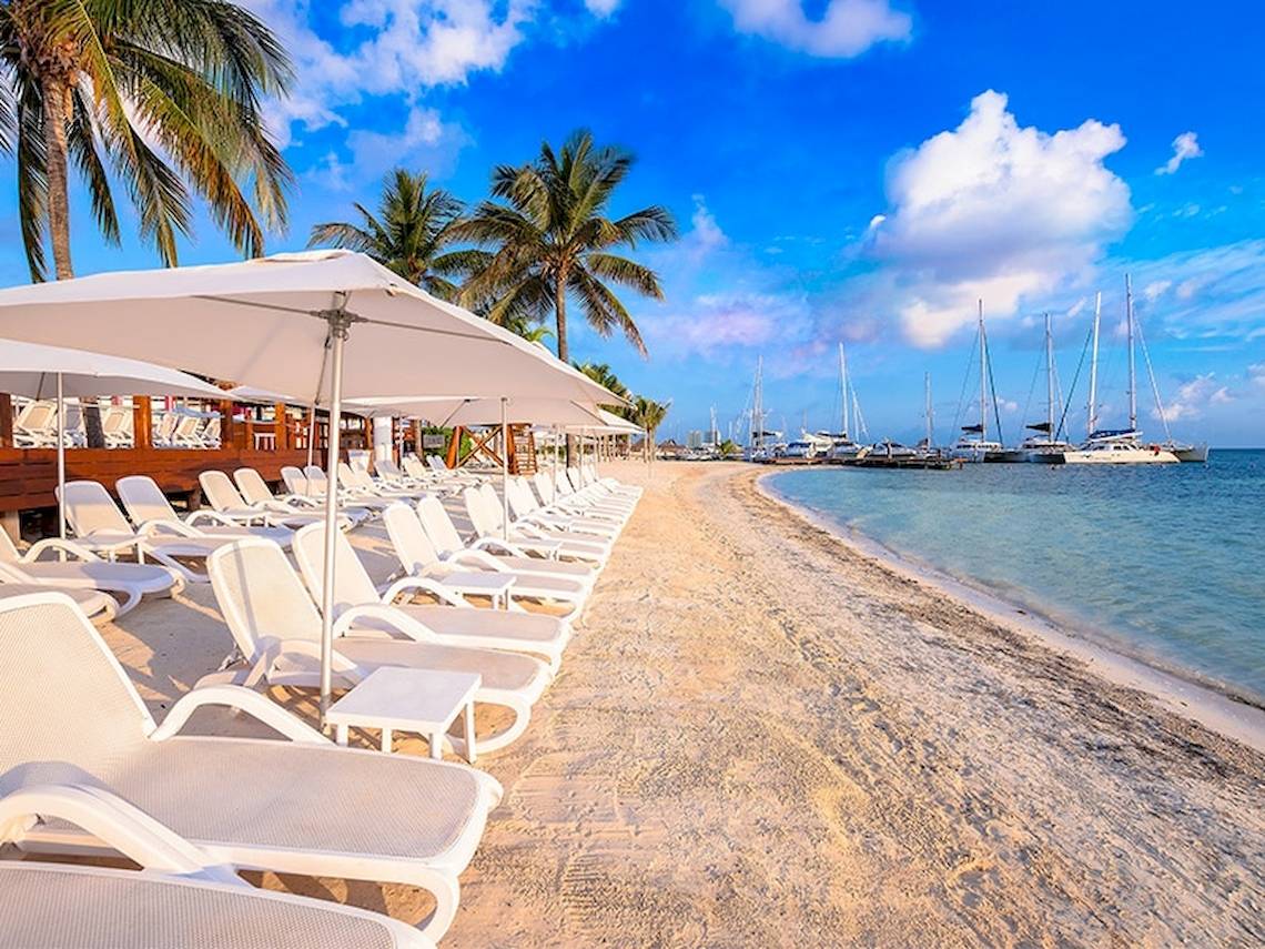 Strand des Temptation Cancun Resorts mit weißen Sonnenliegen und großen Sonnenschirmen