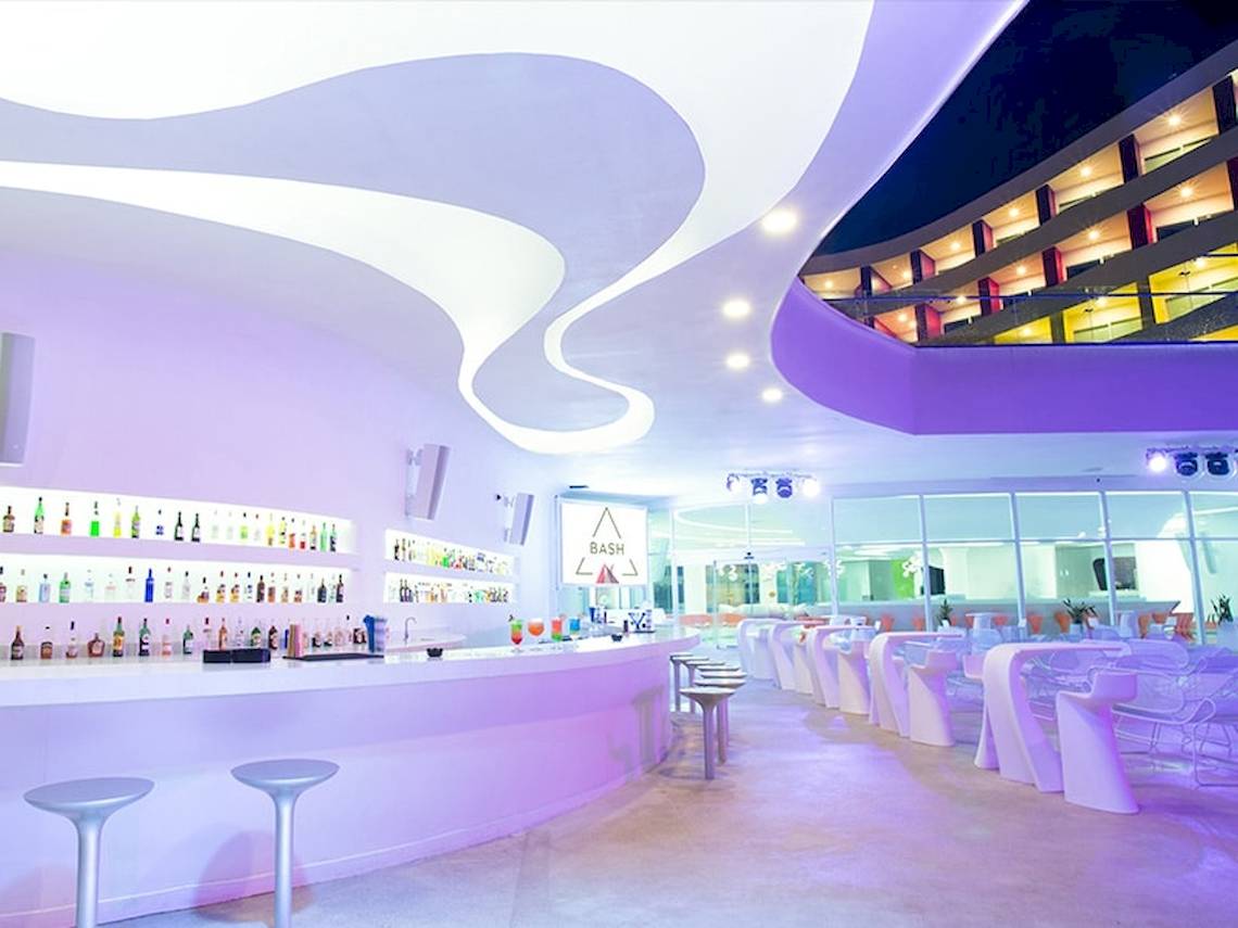 Innenansicht der Bar im Temptation Cancun Resort mit modernem Design, geschwungenen Strukturen und vielen Getränkeflaschen.