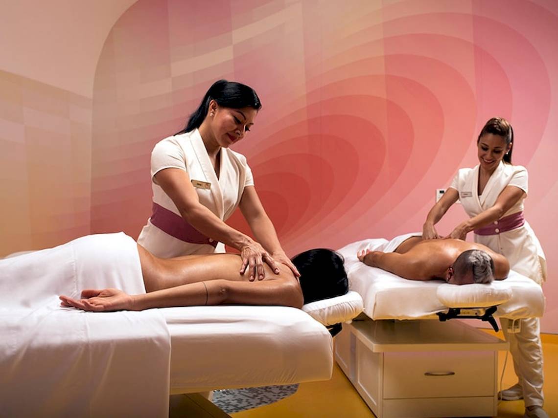 Zwei Frauen im Temptation Cancun Resort geben Massagen an zwei Gästen auf Massagetischen.