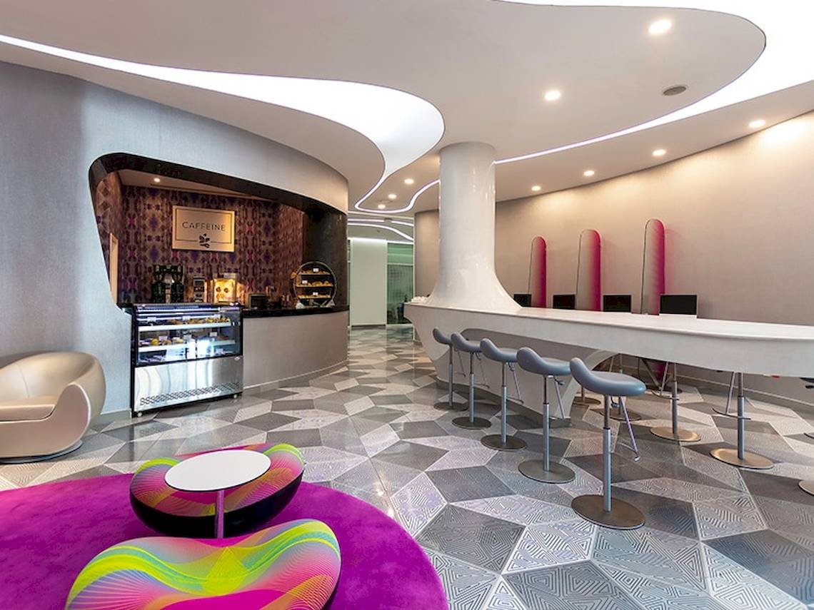 Innenbereich des Temptation Cancun Resorts mit einer Café-Bar, modernen Stühlen und einer gemusterten Bodenfläche.