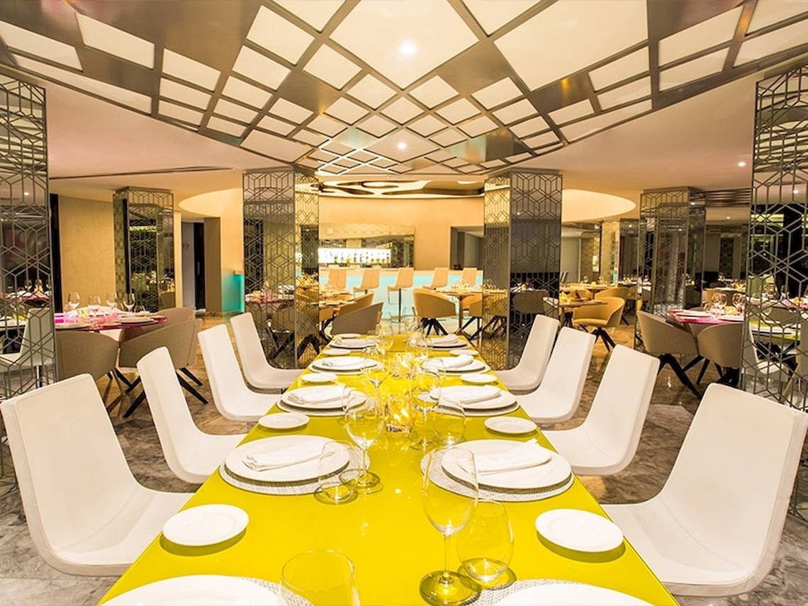 Restaurantbereich im Temptation Cancun Resort mit langer Tafel und weißen Stühlen.